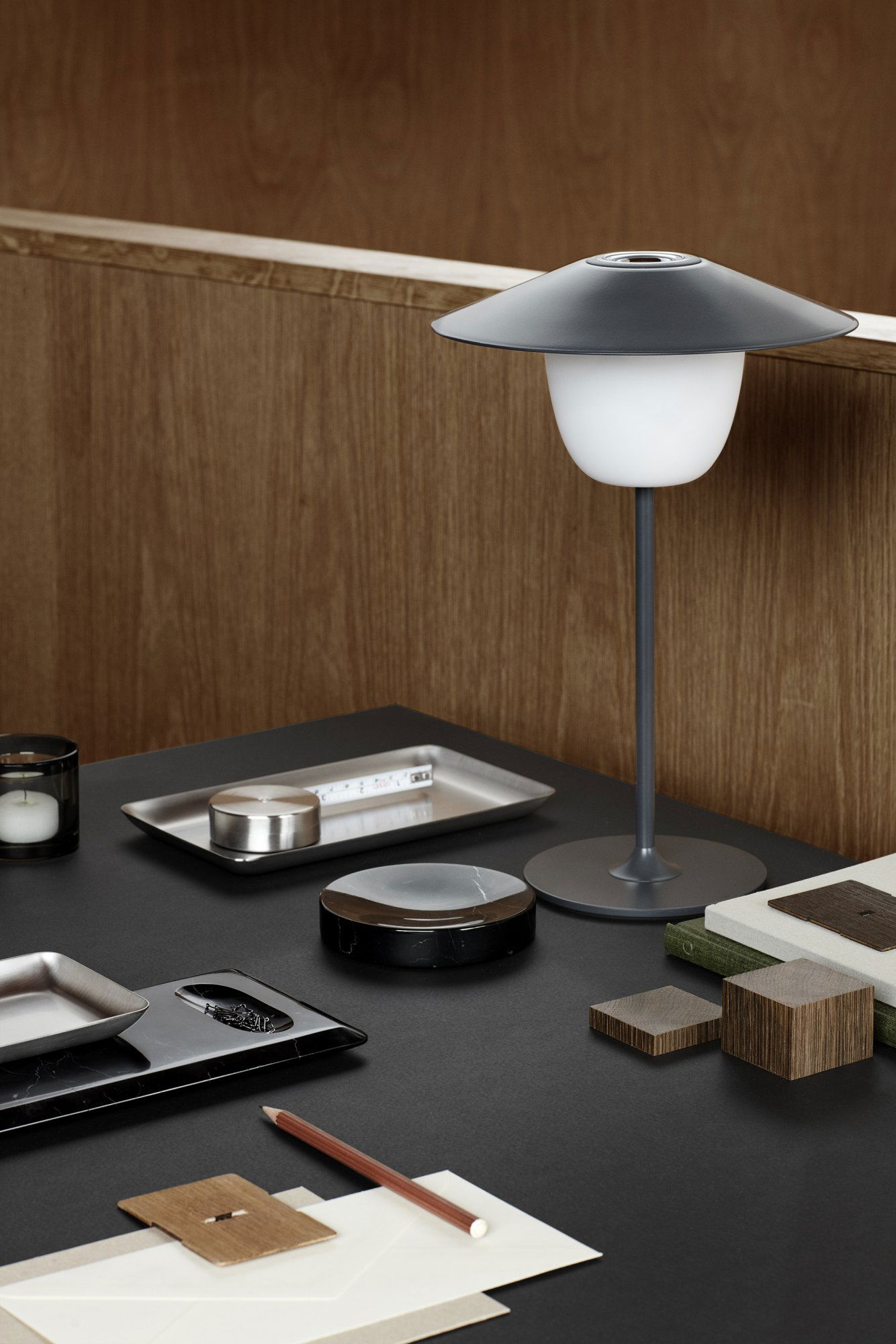 Stilvolle moderne Lampe auf einem Holztisch mit elegantem Geschirr und dekorativen Gegenständen.