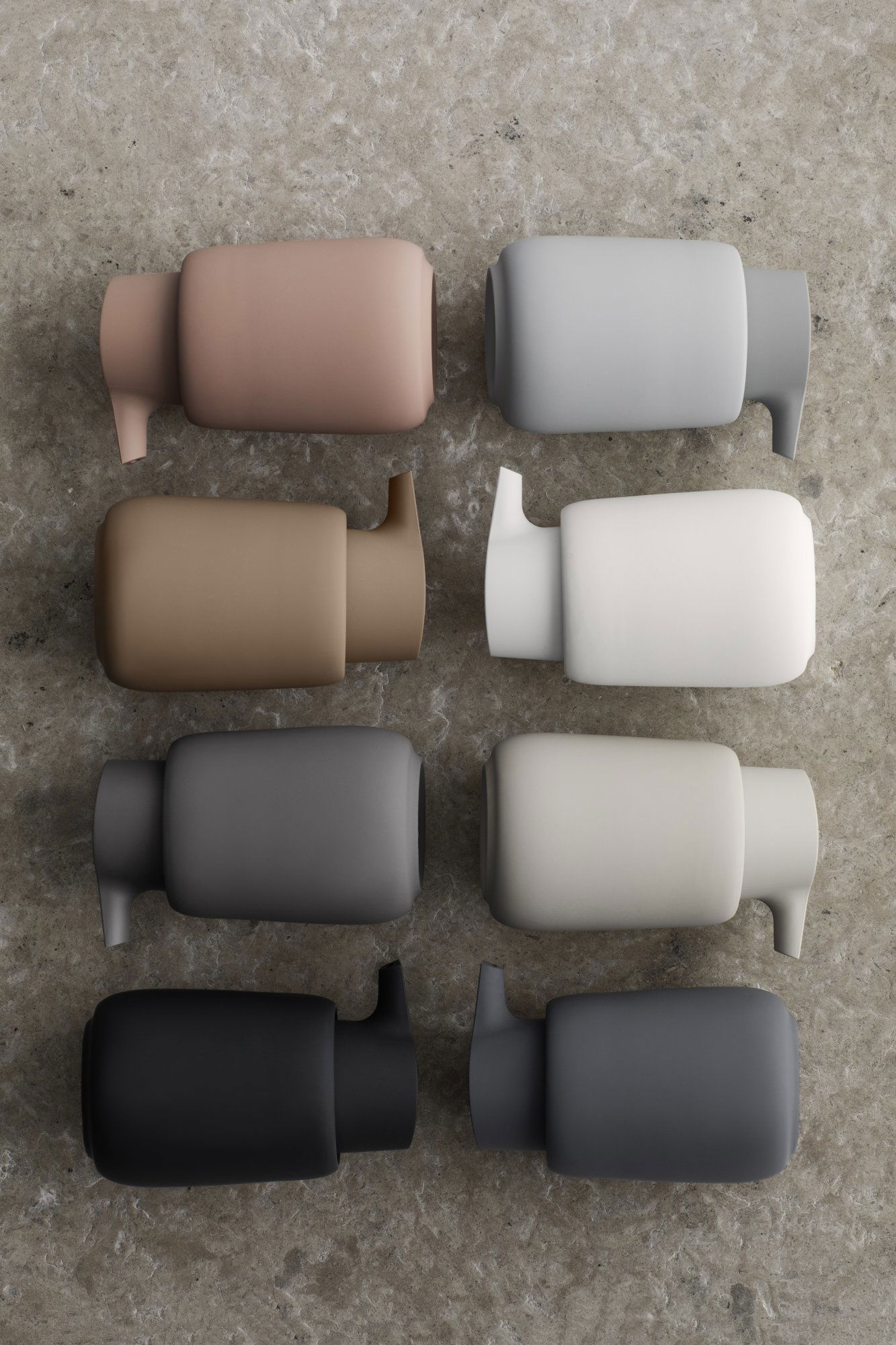 Stilvolle minimalistische Flaschen in neutralen Farben, die auf einer strukturierten Oberfläche angeordnet sind.