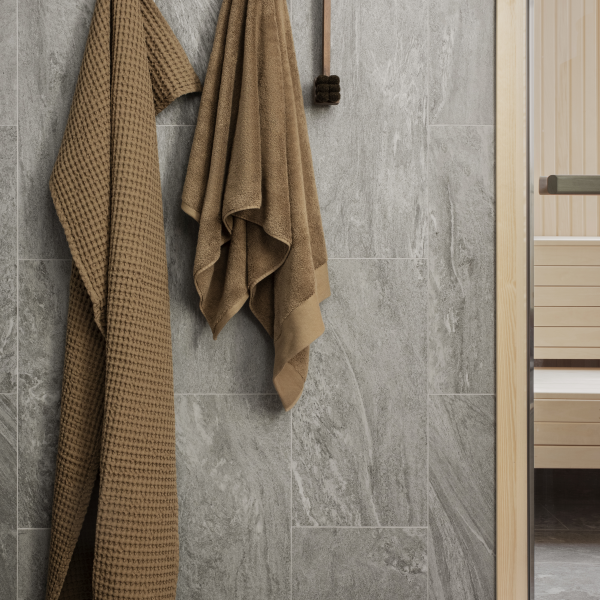 Cozy brown towels hanging on a textured gray bathroom wall next to a sauna.