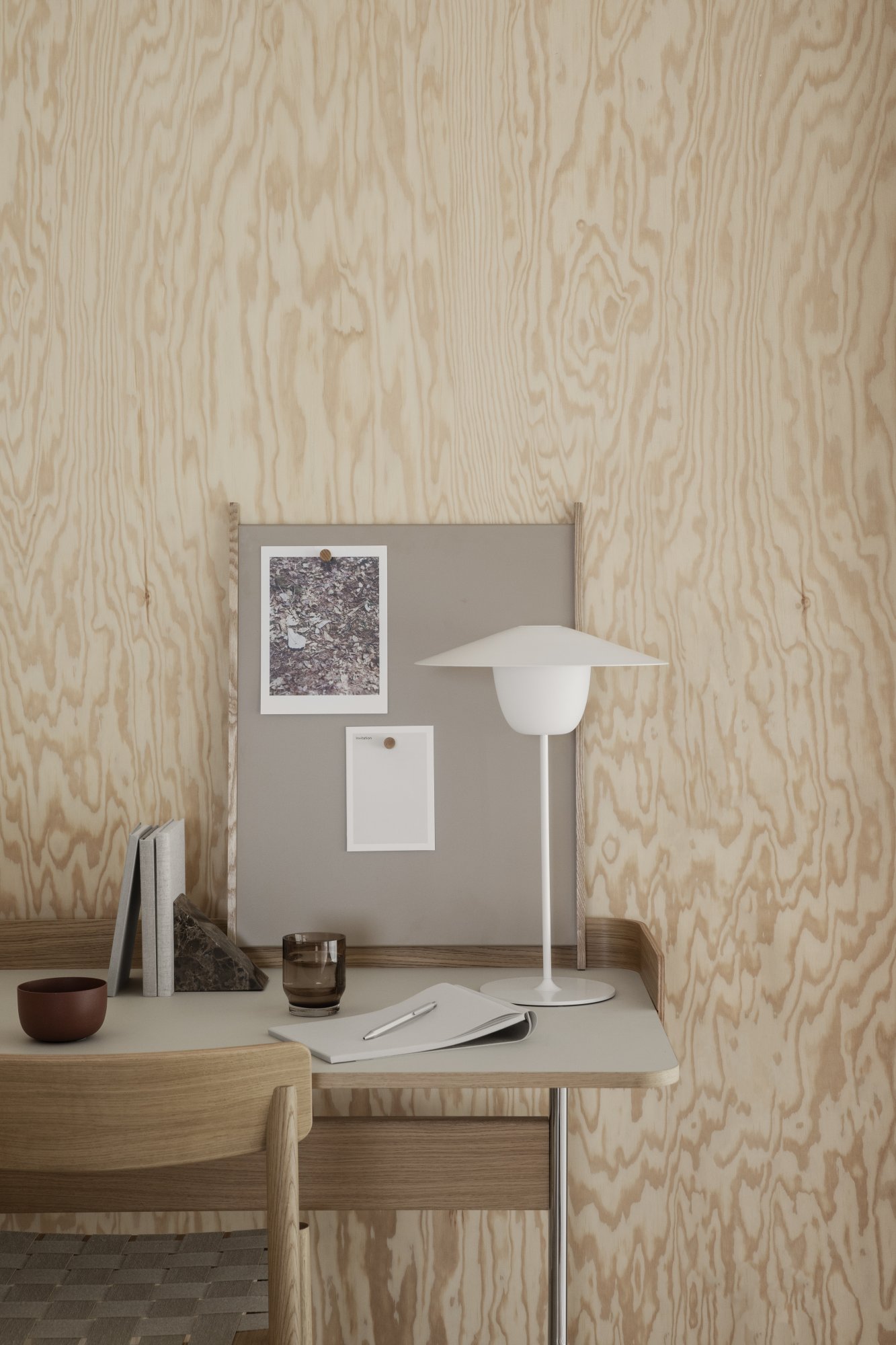 Modern workspace featuring minimalist decor, a lamp, and pinned notes on a soft wood backdrop.