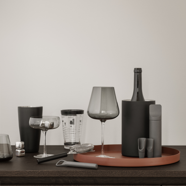 Stylish modern cocktail setup featuring various glasses and bottles on a wooden table.