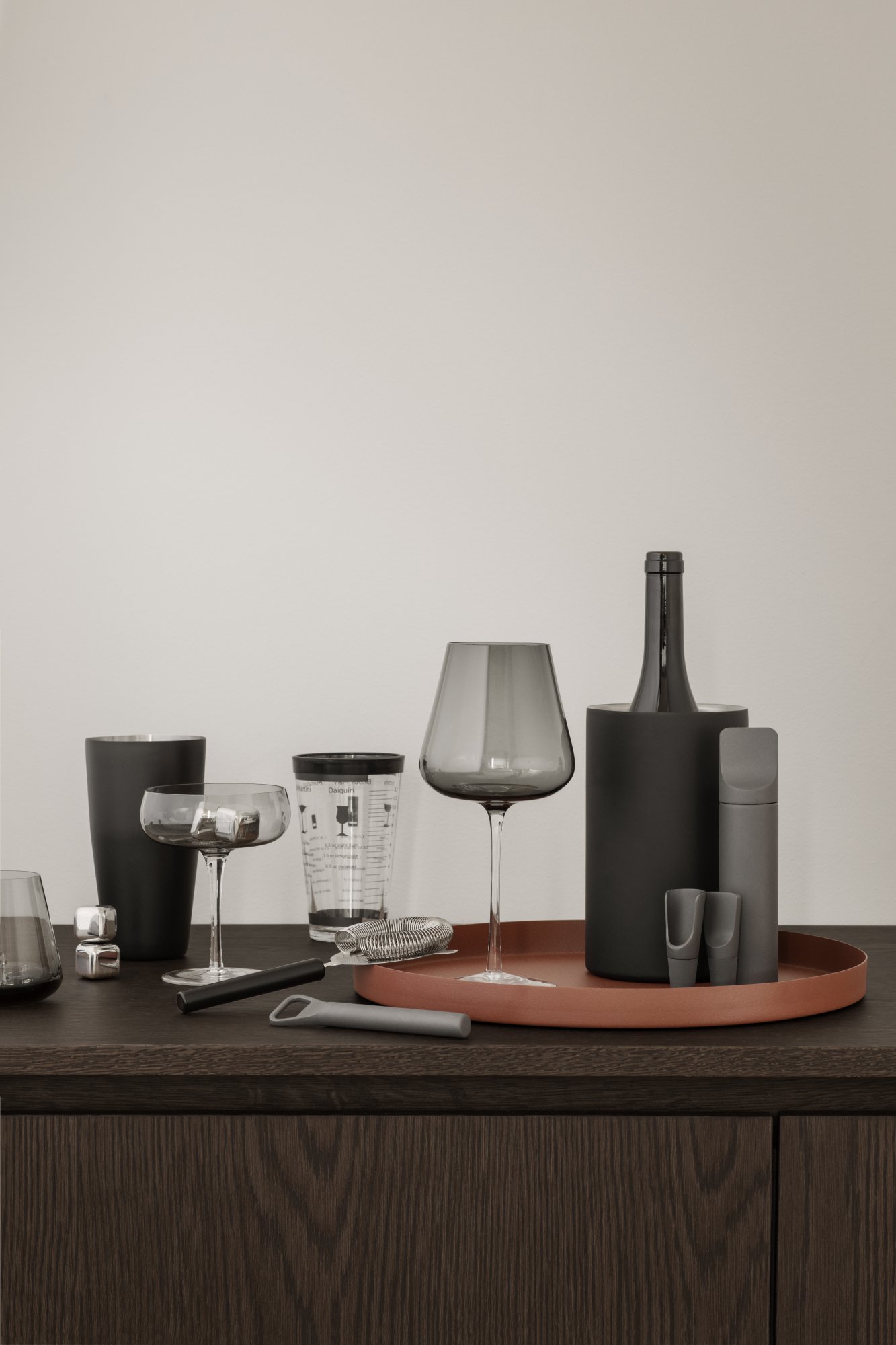 Stylish modern cocktail setup featuring various glasses and bottles on a wooden table.