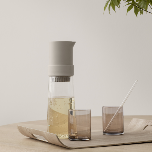 Elegante Glaskaraffe für Wasser mit zwei passenden braunen Gläsern auf einem Holztablett.