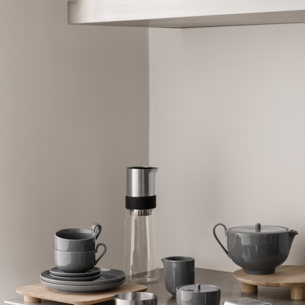 Moderne Kücheneinheit mit stilvollem grauem Geschirr und einer eleganten Kaffeekaraffe.