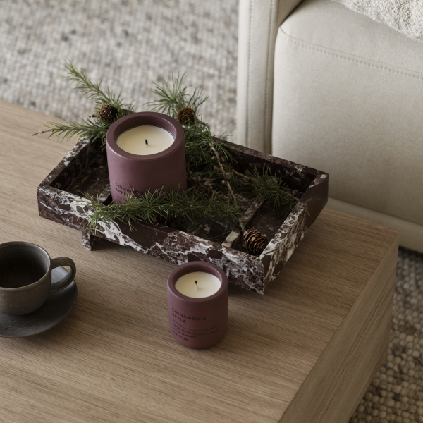 Stylish candles and greenery on a marble tray in a cozy living room setting.