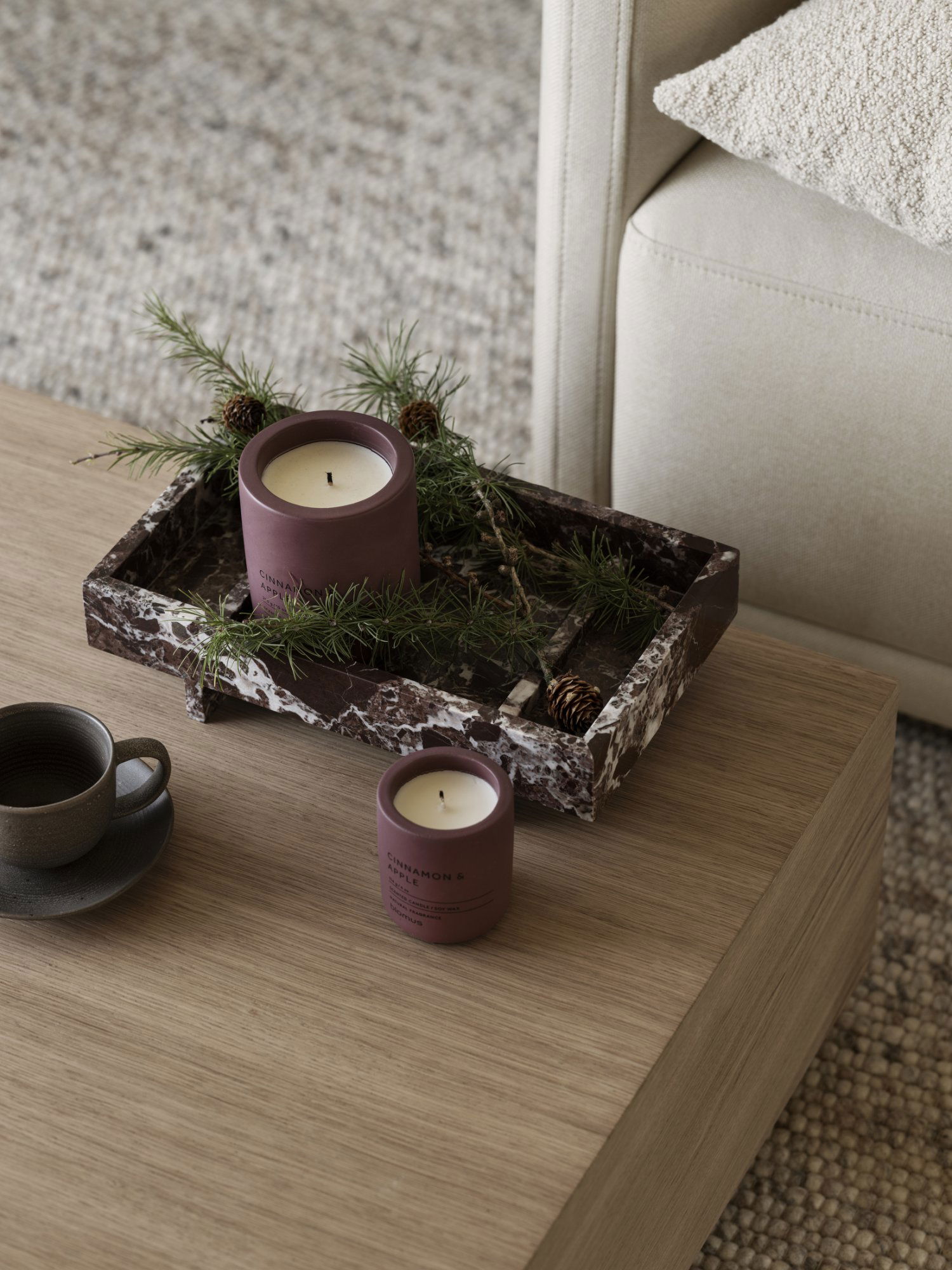 Stylish candles and greenery on a marble tray in a cozy living room setting.
