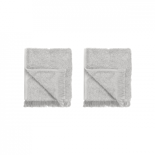 Soft gray towels folded neatly, featuring fringe edges on a black background.