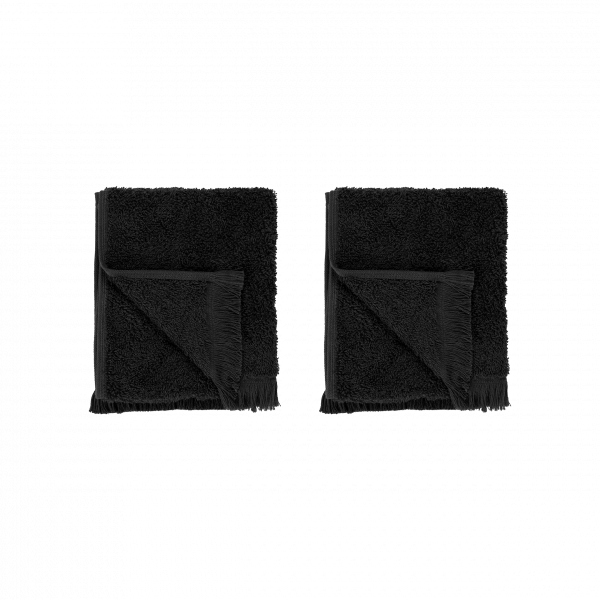 Two plush black towels folded neatly on a black background.