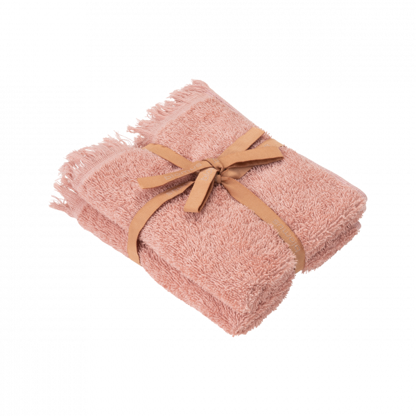 Soft pink towel neatly rolled and tied with a brown ribbon on a black background.