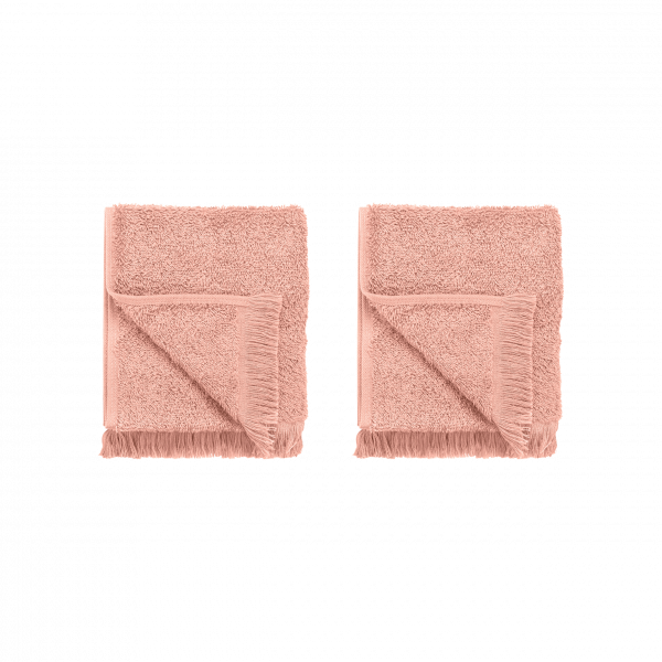 Two plush, coral-colored bath towels neatly folded and displayed on a black background.