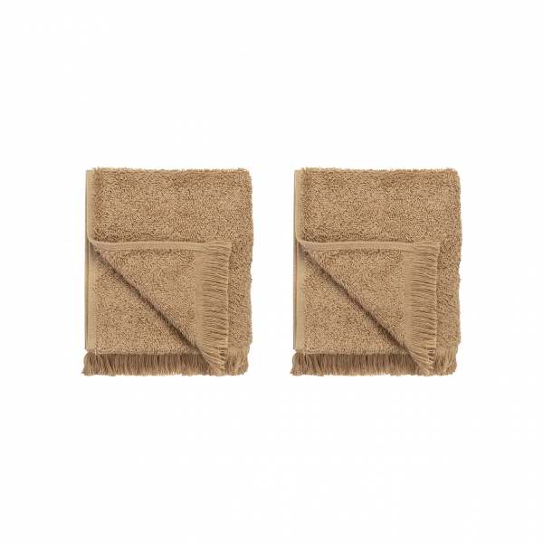 Two folded beige towels with fringed edges on a black background.