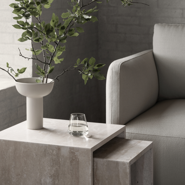 Modern living room scene featuring a minimalist vase, greenery, and a stylish glass on a marble table.