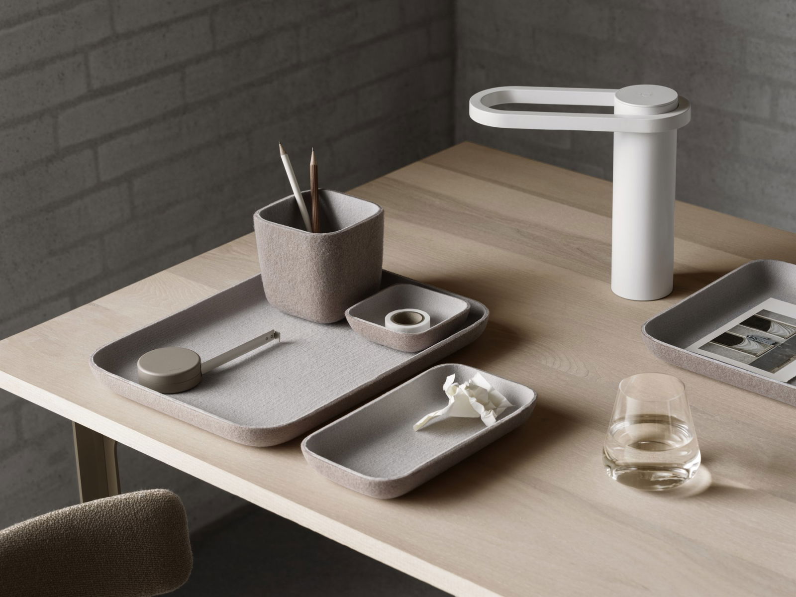 Minimalist desk setup featuring felt trays, a pencil holder, and a stylish lamp.