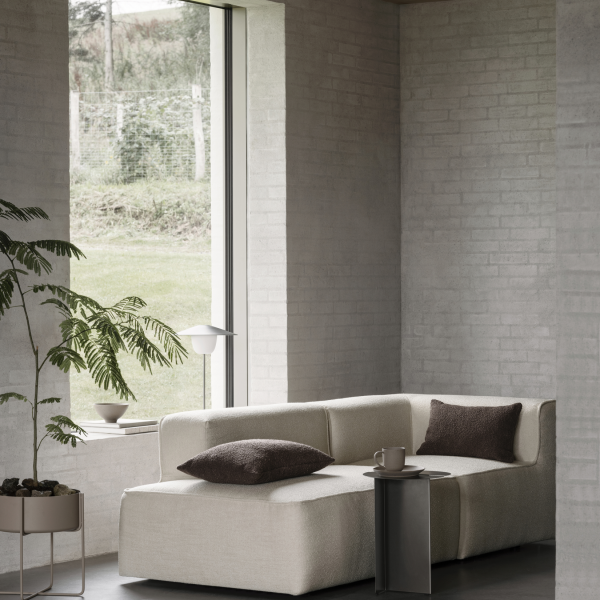 Modernes Wohnzimmer mit einem stilvollen beigen Sofa, minimalistischer Dekoration und großen Fenstern.