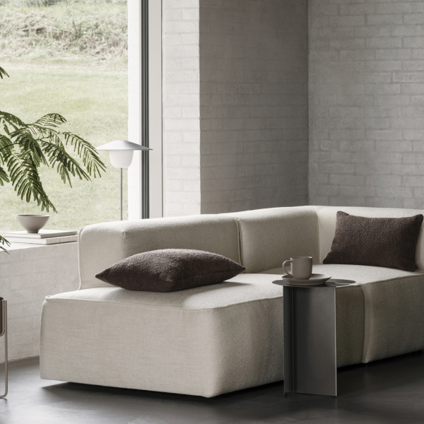 Modernes Wohnzimmer mit einem gemütlichen beigen Sofa, stilvollen Kissen und minimalistischer Dekoration.