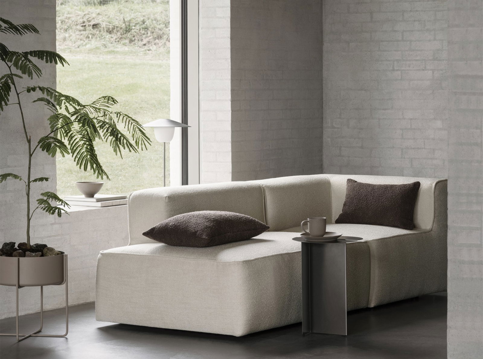 Modernes Wohnzimmer mit einem gemütlichen beigen Sofa, stilvollen Kissen und minimalistischer Dekoration.