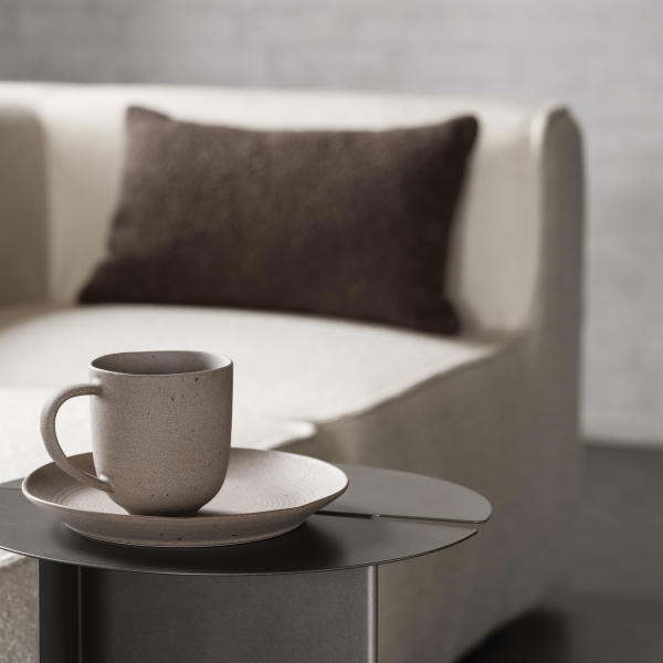 Gemütliche Wohnzimmerszene mit einem neutralen Becher und Teller auf einem eleganten Beistelltisch neben einem Sofa.