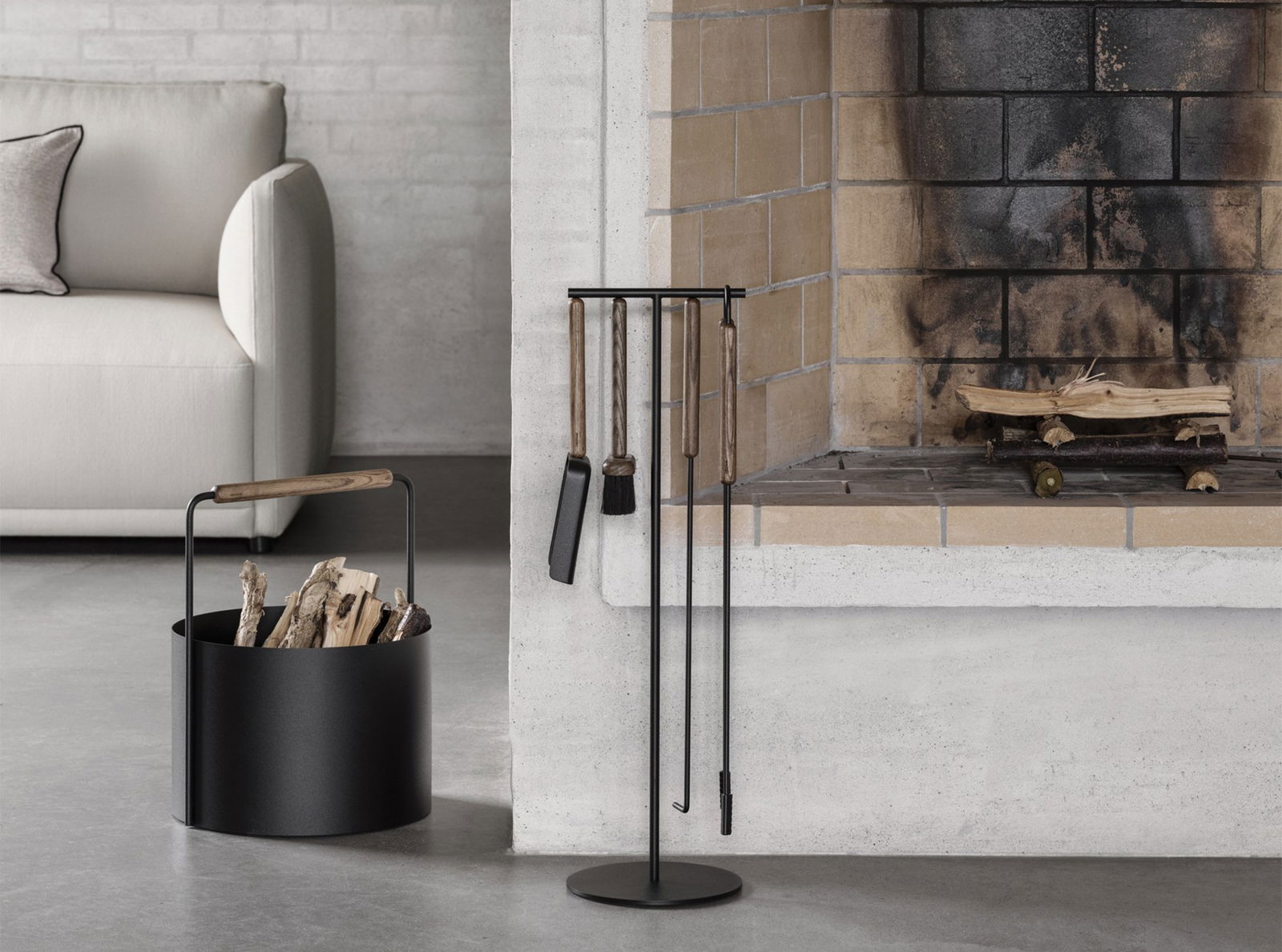 Modern fireplace tools displayed near a cozy stone fireplace and log holder.
