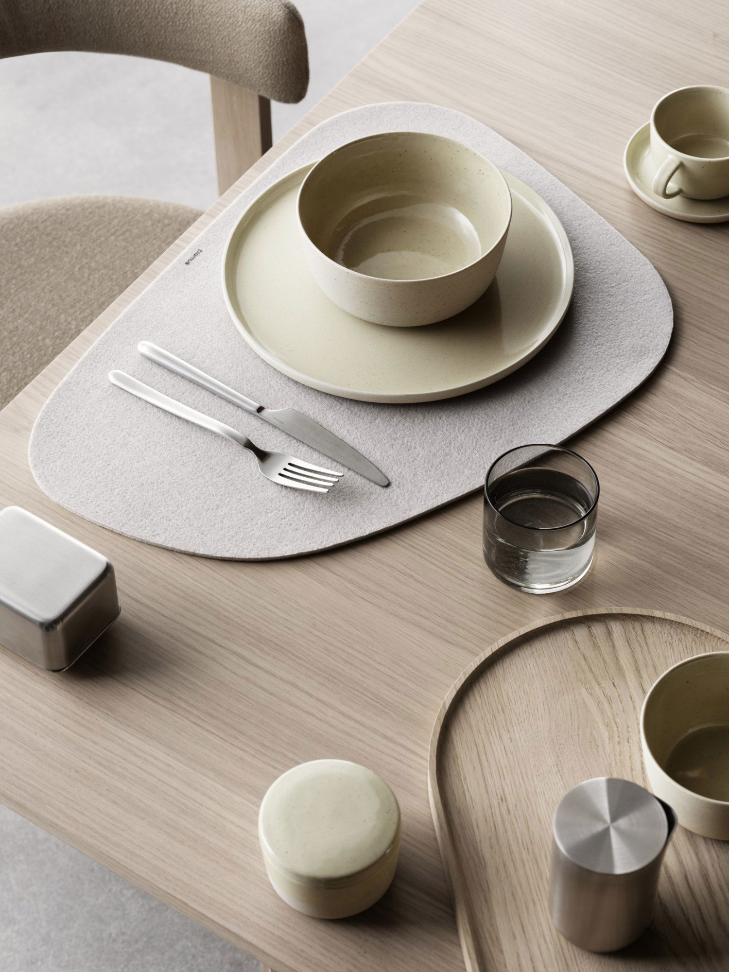 Moderne Essbereich mit minimalistischem Geschirr und stilvoller Tischunterlage auf einem Holztisch.
