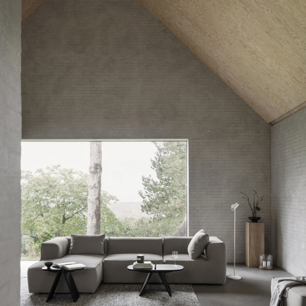 Modern living room with a gray sectional sofa and large window overlooking greenery.