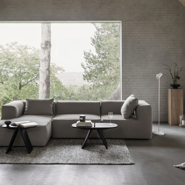 Modernes Wohnzimmer mit einem grauen Sofa, minimalistischer Dekoration und großem Fenster mit Blick auf die Natur.