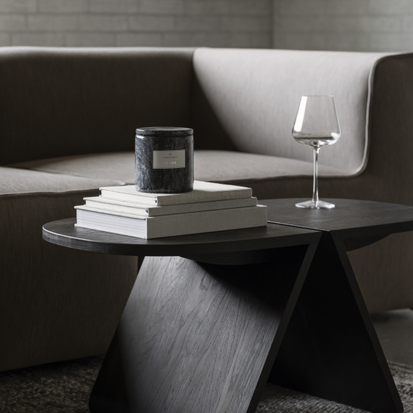 Moderne Wohnzimmergestaltung mit einer stilvollen Kerze, einem Glas und gestapelten Büchern auf einem eleganten Tisch.