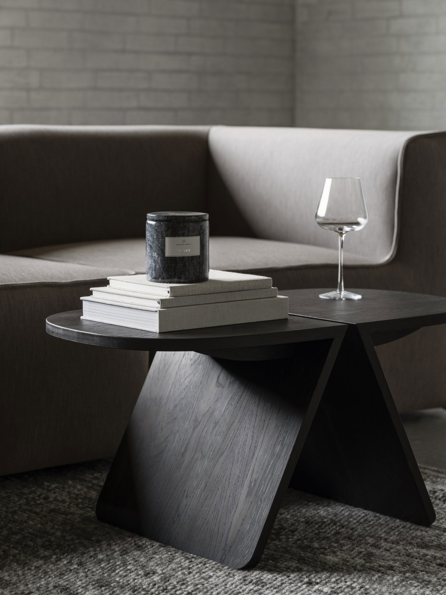 Moderne Wohnzimmergestaltung mit einer stilvollen Kerze, einem Glas und gestapelten Büchern auf einem eleganten Tisch.