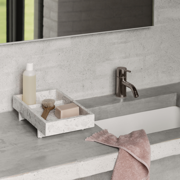 Modern bathroom sink with a stone tray holding soap, a brush, and a bottle, complemented by a towel.