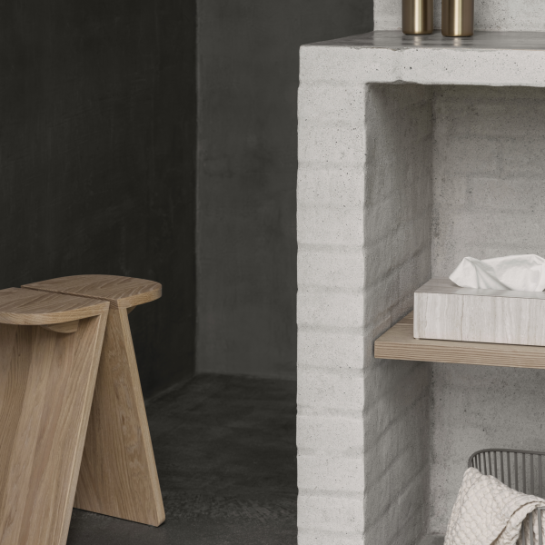 Elegant minimalist living space featuring a concrete shelf and wooden stool.