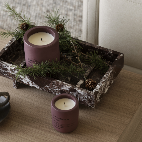 Elegant candles in a marble tray adorned with pine and pine cones, perfect for cozy decor.