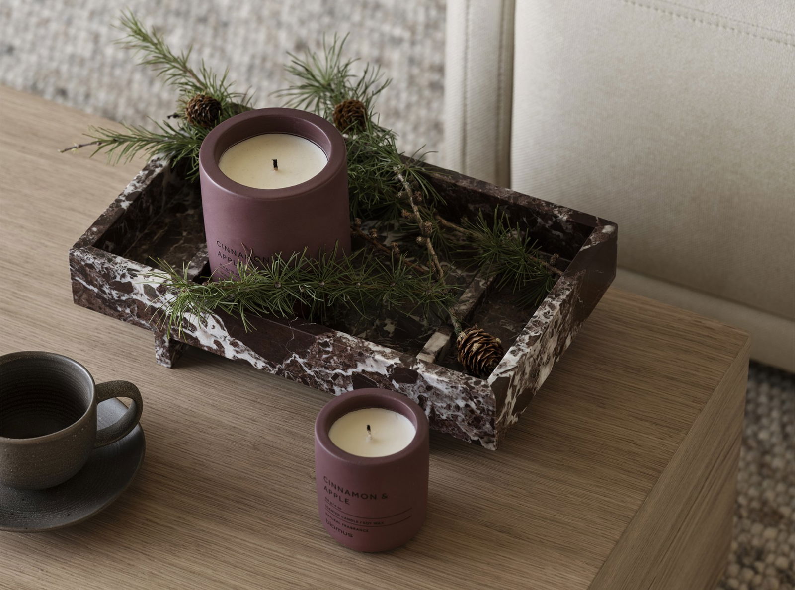 Elegant candles in a marble tray adorned with pine and pine cones, perfect for cozy decor.