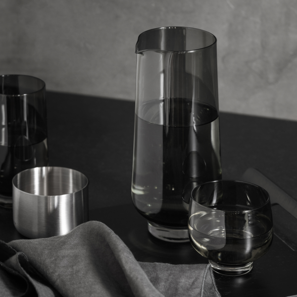 Elegantes Glasgeschirrset mit einer Kanne und Gläsern auf einem stilvollen schwarzen Tisch.