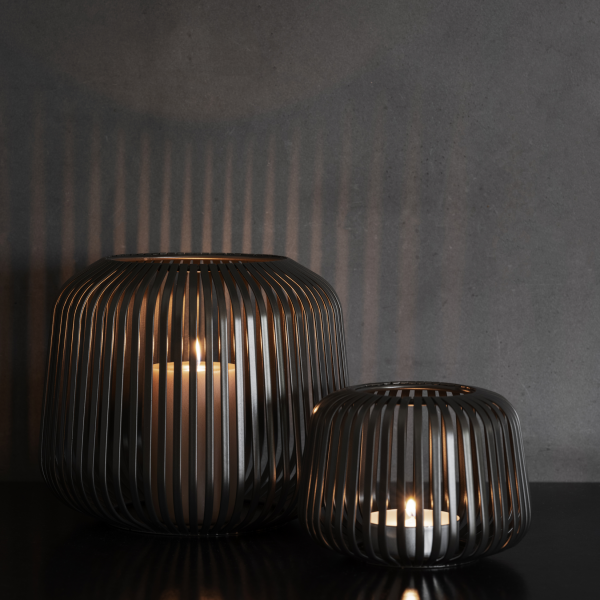Elegante Metallkerzenhalter, die warme Schatten auf einem dunklen Wandhintergrund werfen.