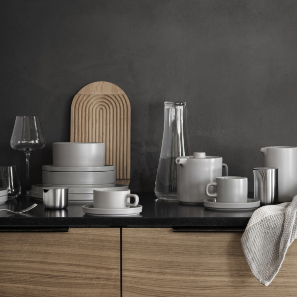 Stylisches graues Geschirr und Gläser auf einer modernen Küchentheke mit Holzakzenten ausgestellt.