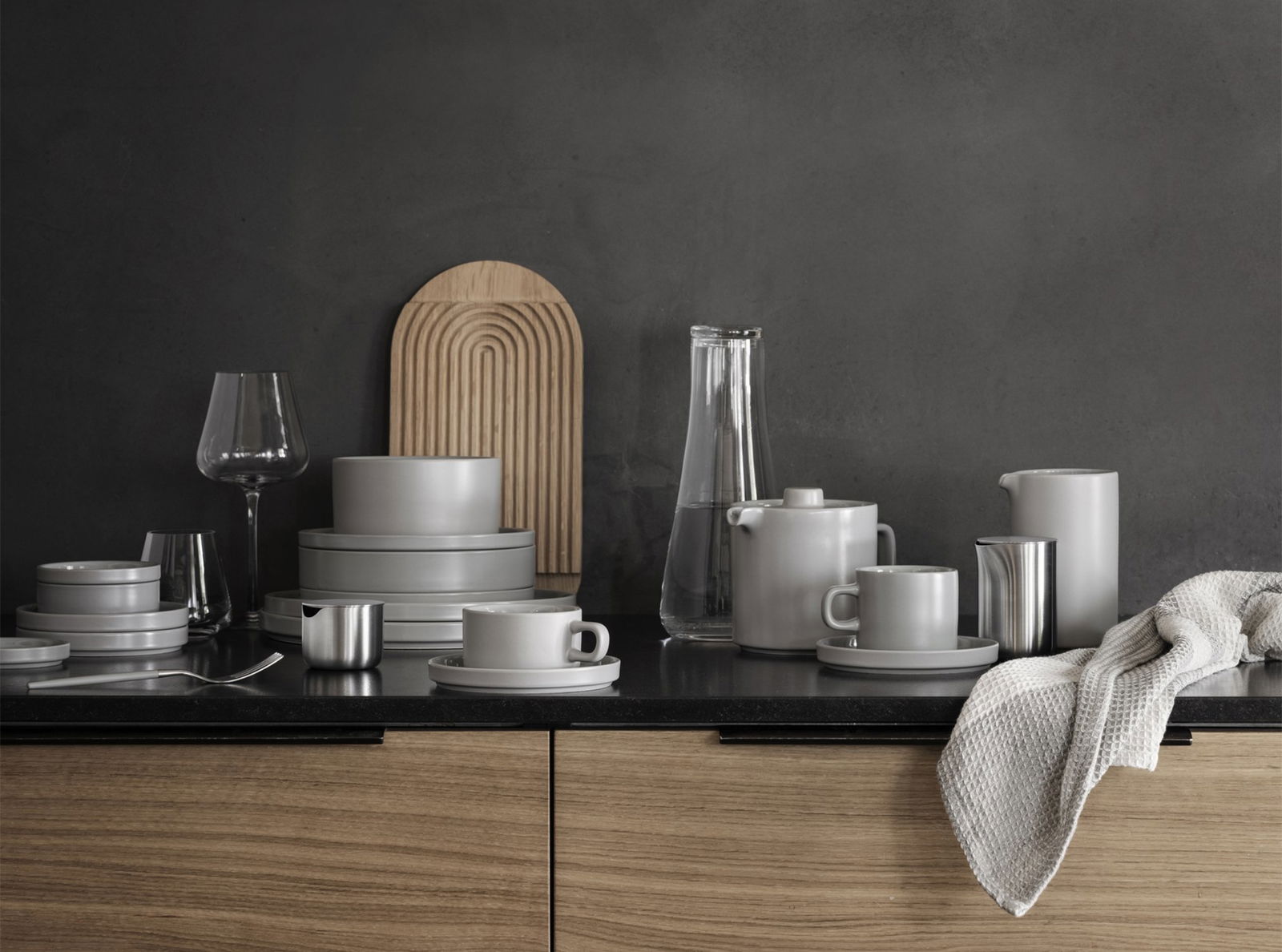 Stylisches graues Geschirr und Gläser auf einer modernen Küchentheke mit Holzakzenten ausgestellt.