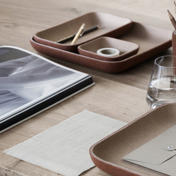 Minimalistischer Arbeitsplatz mit Organizern, Notizbuch und einem Glas Wasser auf einem Holztisch.
