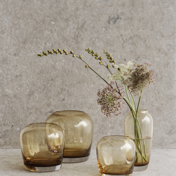 Elegant glass vases with flowers against a textured gray background.