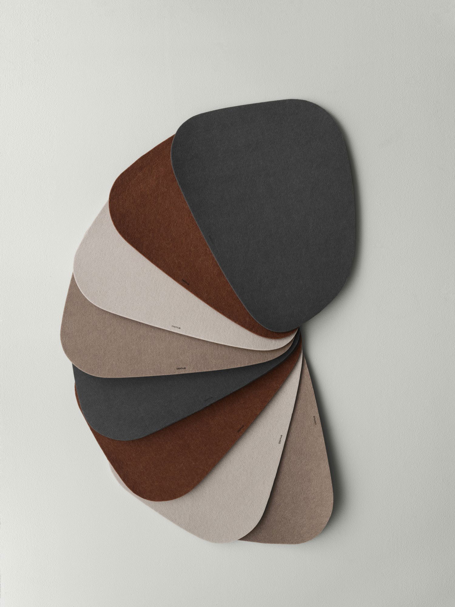 Colorful felt material swatches in various shapes and shades displayed on a wall.