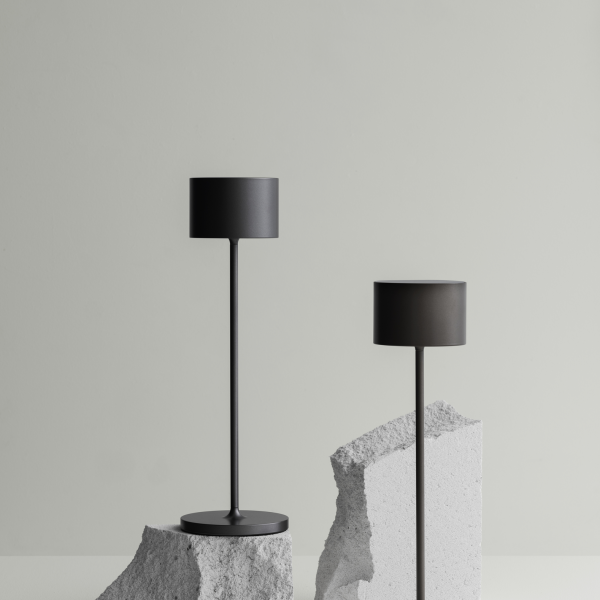 Stylish modern black lamps on textured stone bases in minimalistic interior design.