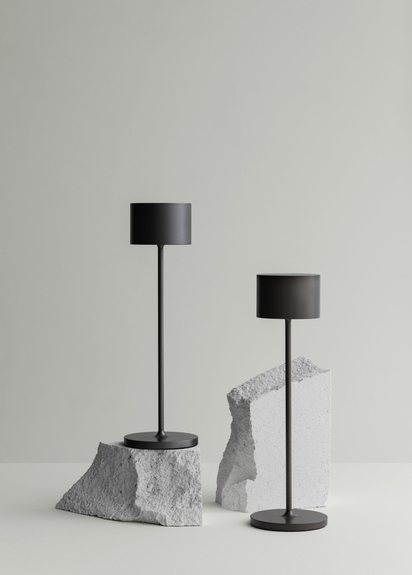 Stylish modern black lamps on textured stone bases in minimalistic interior design.