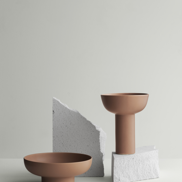 Minimalistische Keramikschalen, die auf strukturierten Steinoberflächen vor einem sanften grauen Hintergrund präsentiert werden.