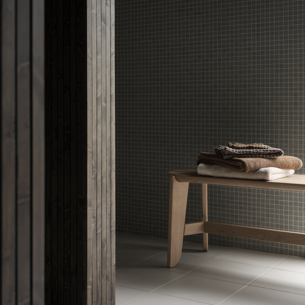 A minimalist bathroom scene featuring a wooden bench with neatly stacked towels.