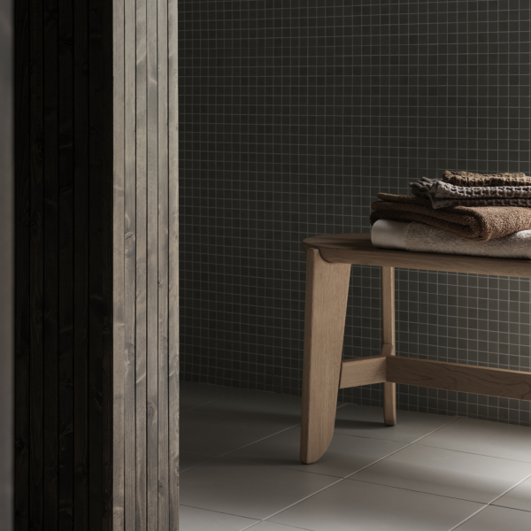 Minimalist bathroom featuring wooden bench with neatly stacked towels against a textured wall.