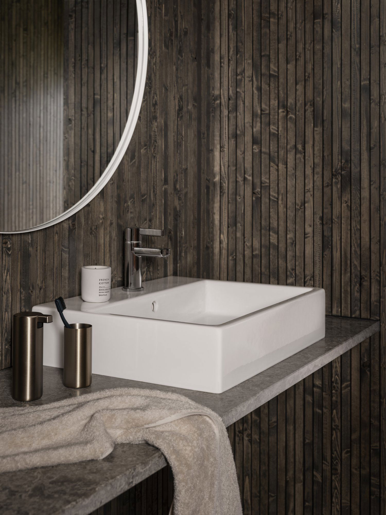 Modernes Badezimmerwaschbecken mit schlankem Design, dunklen Holzwänden und stilvollen Accessoires.