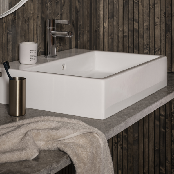 Modernes Badezimmerwaschbecken mit sleekem Design an einer strukturierten Holzwand.