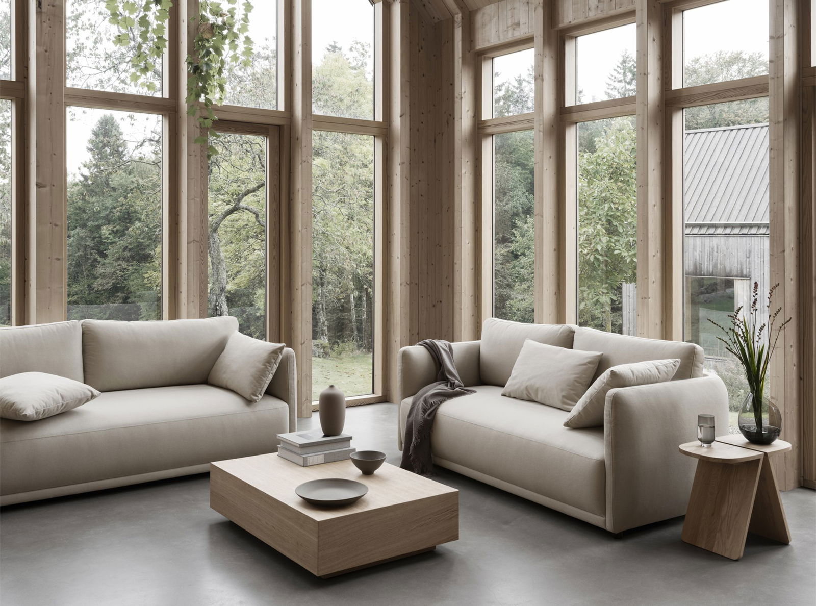 Gemütliches Wohnzimmer mit modernen beigen Sofas und einem Holztisch neben großen Fenstern.