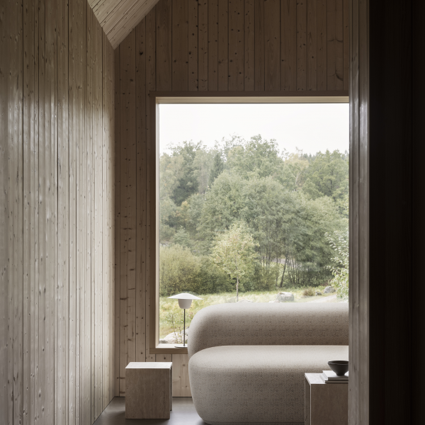 Cozy interior with a modern sofa and large window overlooking a serene nature view.