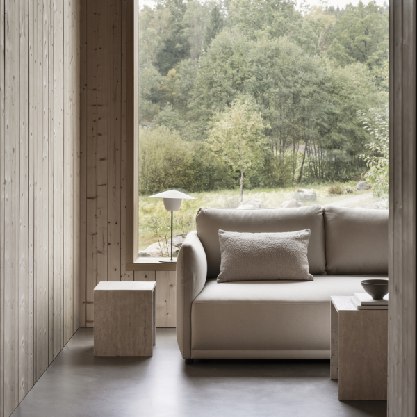 Modern interior with a cozy sofa and natural scenery visible through large windows.