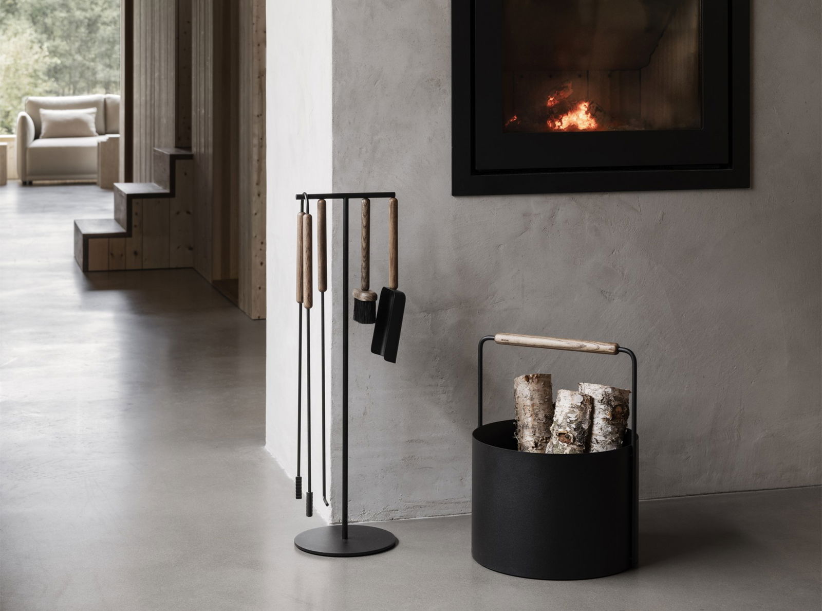 Modern fireplace tools and firewood holder next to a stylish, minimalist living space.