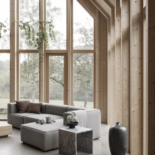 Moderner Wohnraum mit großen Fenstern, minimalistischer Möbeln und Akzenten aus Naturholz.